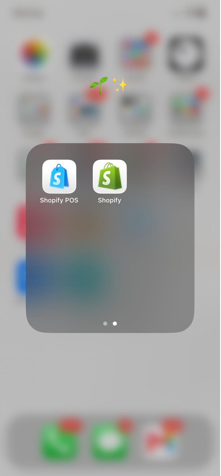 iPhone home screen showing a folder containing both Shopify POS and Shopify app icons side by side